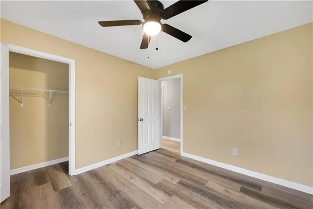 an empty room with wooden floor closet and ceiling fan