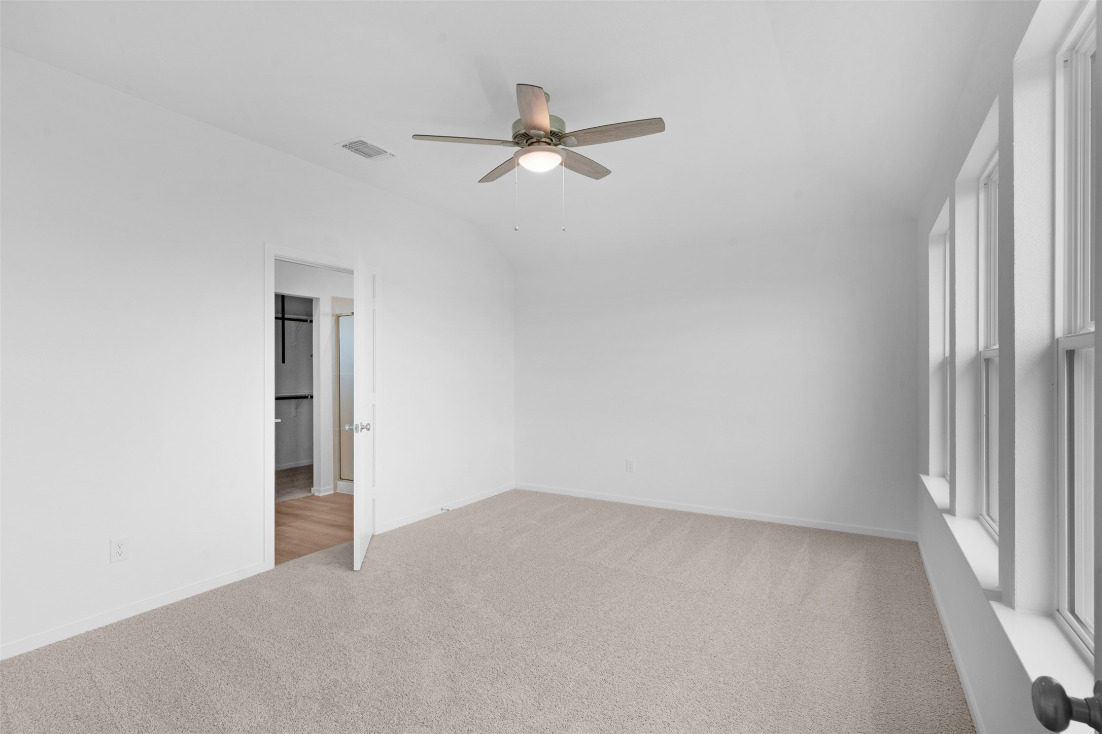 13701 Tucker Hedge Pass Elgin, TX 78621 - Photo 13 of 21 Carpeted room featuring a ceiling fan with integrated lighting, three large windows, and a doorway leading to a closet with wood-finish flooring