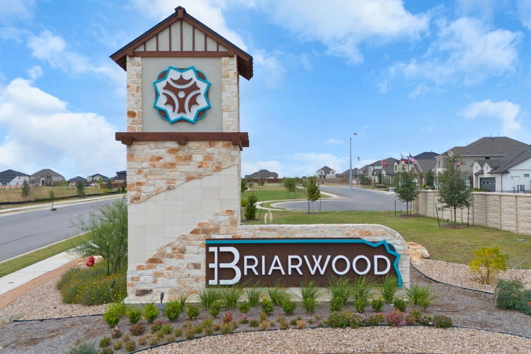 13701 Tucker Hedge Pass Elgin, TX 78621 - Photo 20 of 21 Community entrance sign featuring stacked stone and stucco construction with decorative landscaping