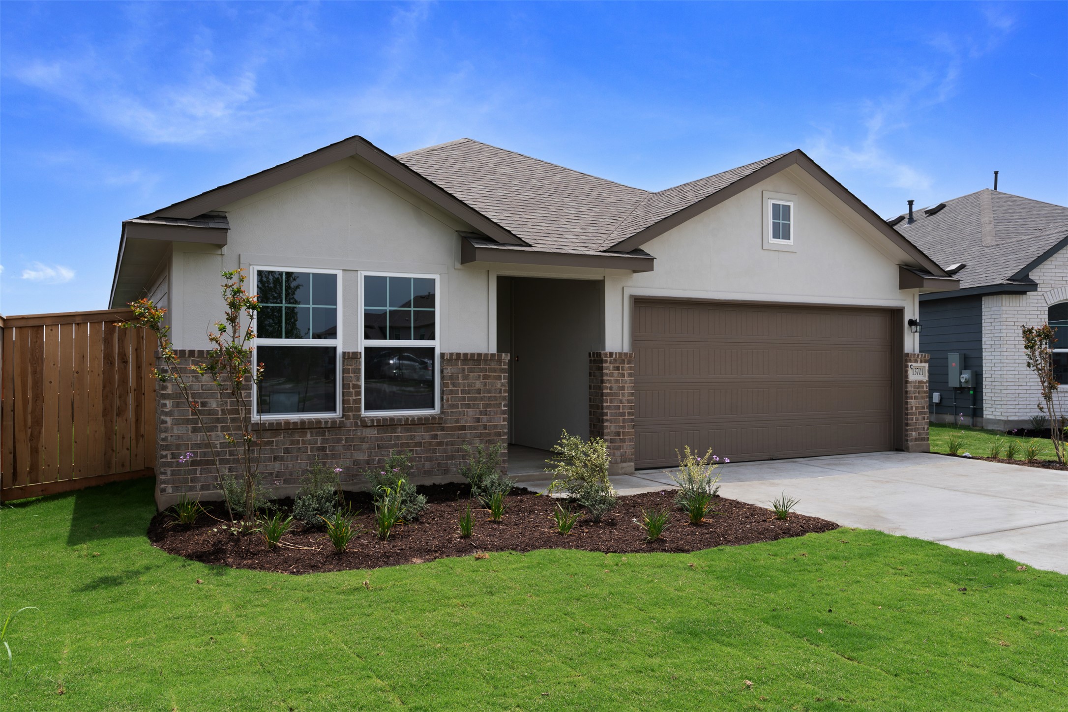 13701 Tucker Hedge Pass Elgin, TX 78621 - Photo 5 of 21 Contemporary single-story residence featuring a two-car garage, partial brick facade, light stucco siding, and a gabled roofline