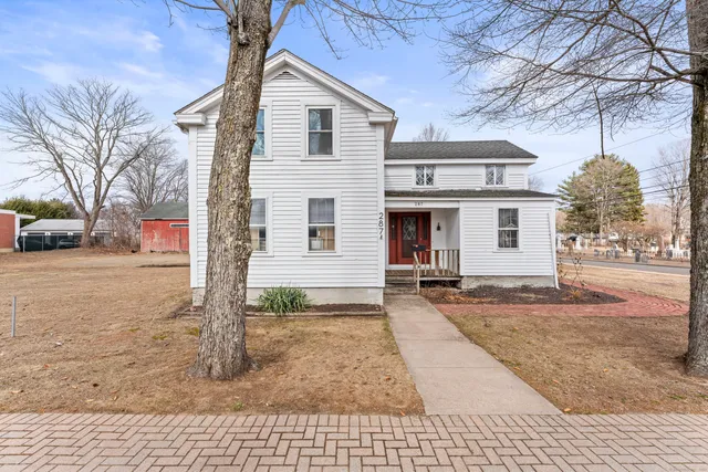 a view of a white house with a large tree