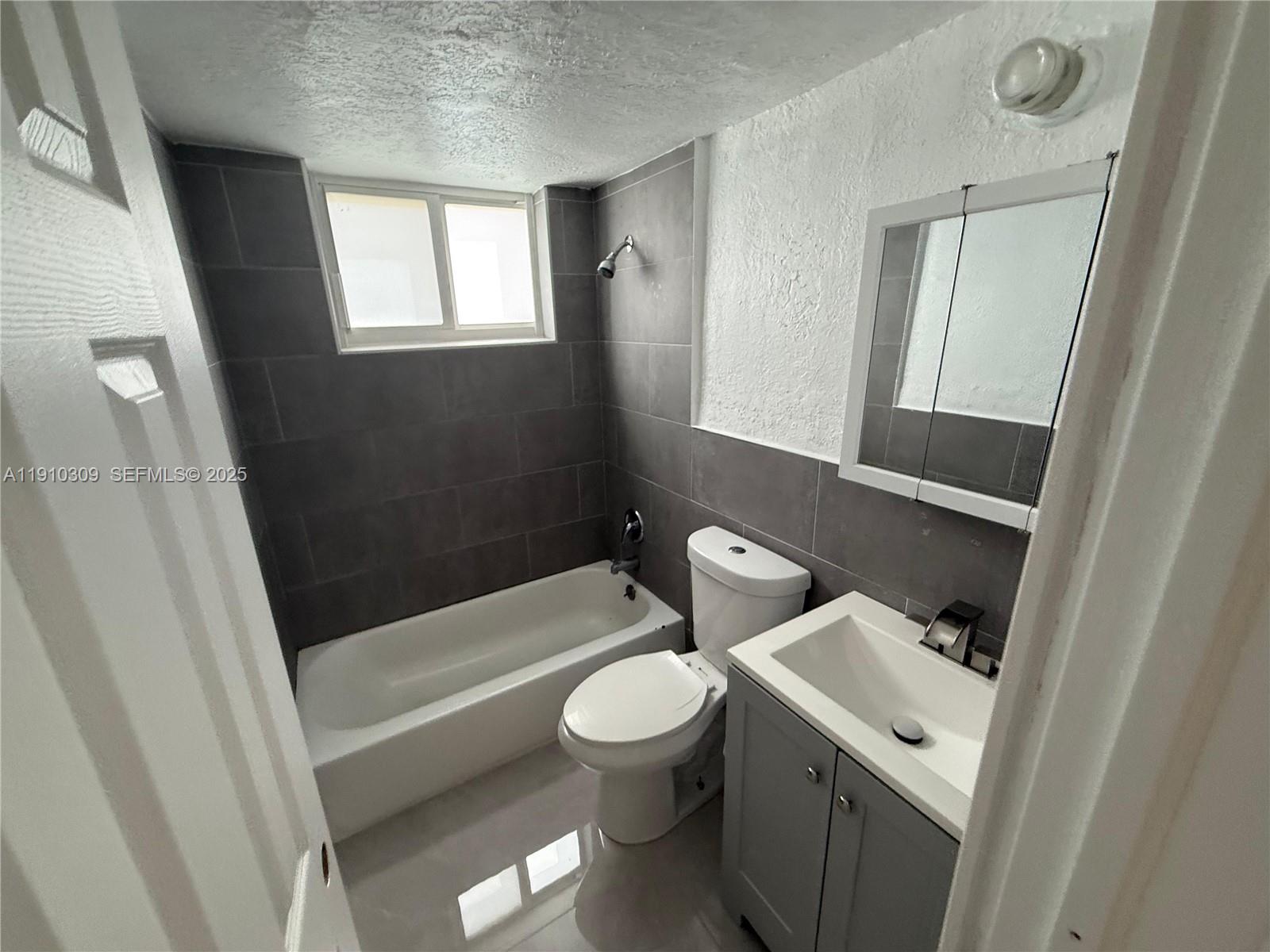 1251 Northwest 61st Street, Unit 5 Miami, FL 33142 - Photo 9 of 15 a white toilet sitting next to a bath tub