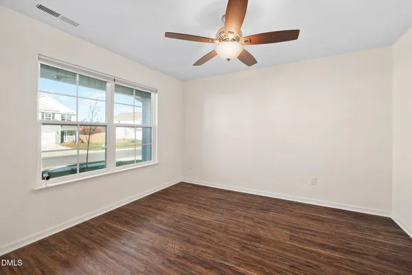 an empty room with wooden floor fan and windows