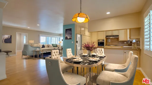 a kitchen with stainless steel appliances kitchen island granite countertop a stove a sink a refrigerator dining table and chairs