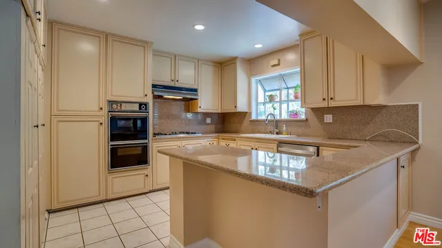 a kitchen with granite countertop a sink stove and cabinets