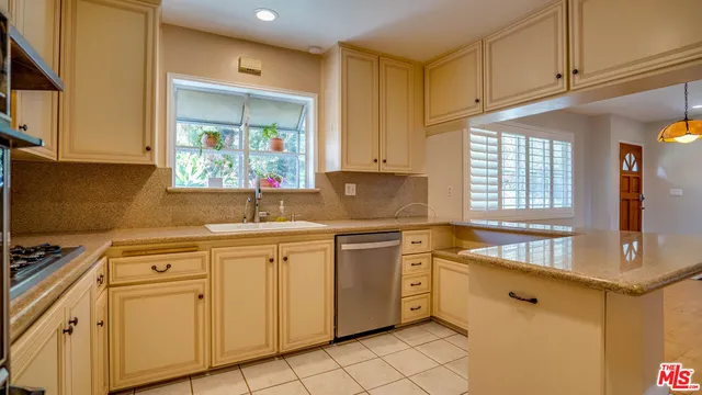 a large kitchen with stainless steel appliances granite countertop a stove a sink a refrigerator and a view of living room