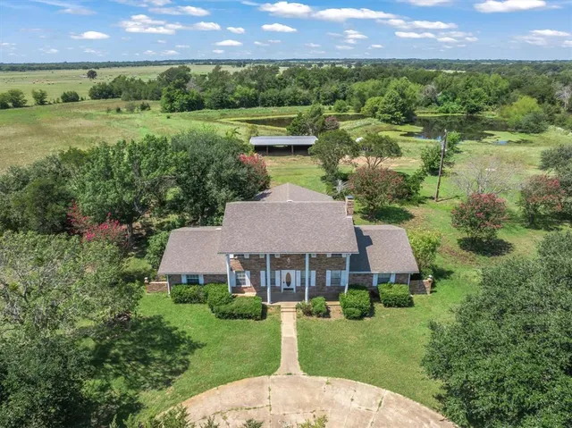 a aerial view of a house with a yard and a large pool