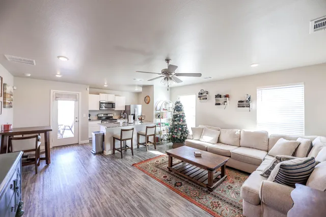 a living room with furniture a wooden floor and a view of kitchen