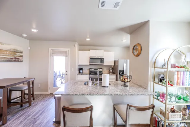 a kitchen with stainless steel appliances granite countertop a dining table chairs and stove top oven with wooden floor