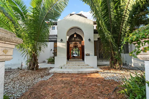 a view of a stone house with a yard and large tree