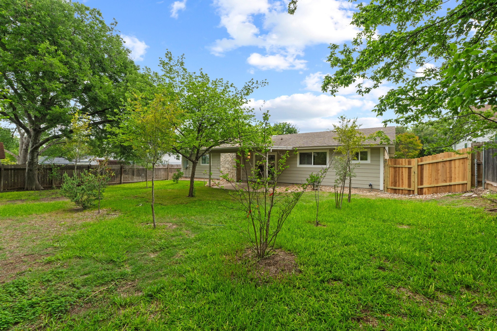 1608 Springer Lane Austin, TX 78758 - Photo 34 of 35 Expansive backyard featuring a manicured lawn, established trees, and a wooden privacy fence