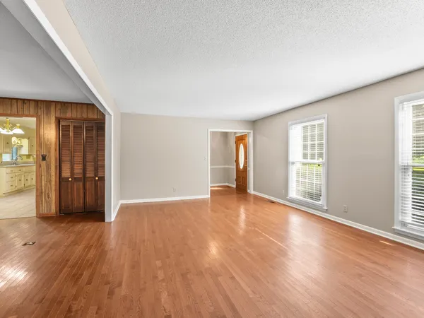 a view of an empty room with wooden floor and closet