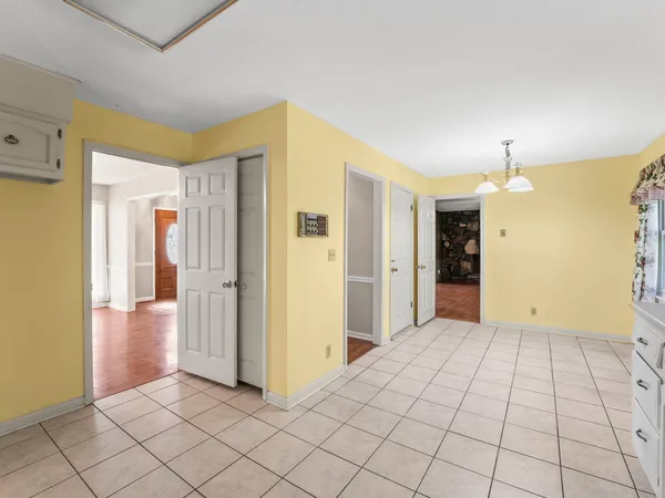 a view of an empty room with chandelier fan and wooden floor