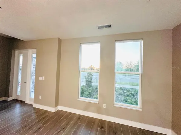 a view of an empty room with wooden floor and a window