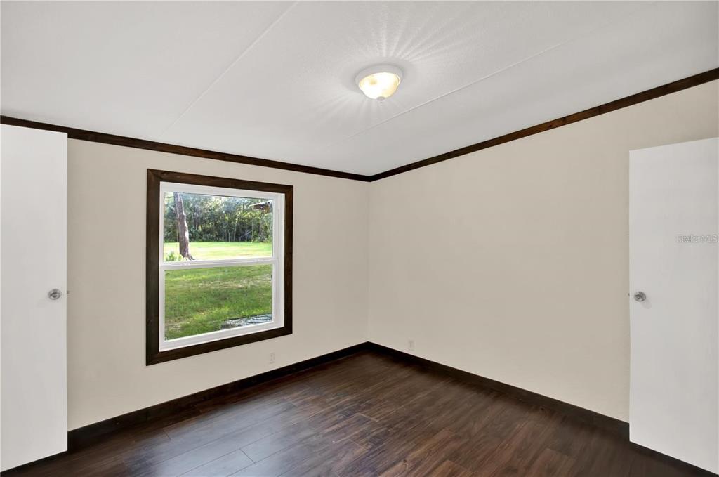 10650 Northwest 190th Street Micanopy, FL 32667 - Photo 22 of 31 a view of an empty room with wooden floor and a window