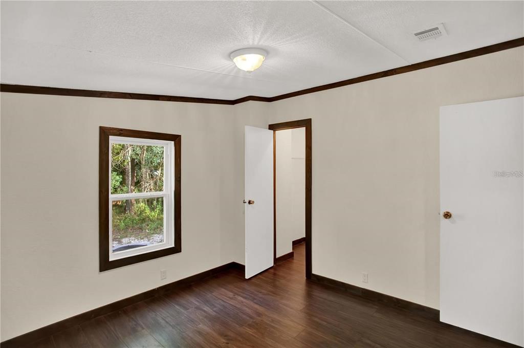 10650 Northwest 190th Street Micanopy, FL 32667 - Photo 25 of 31 a view of an empty room with wooden floor and a window