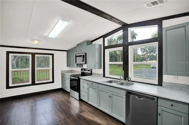 a kitchen with sink a large window and stainless steel appliances