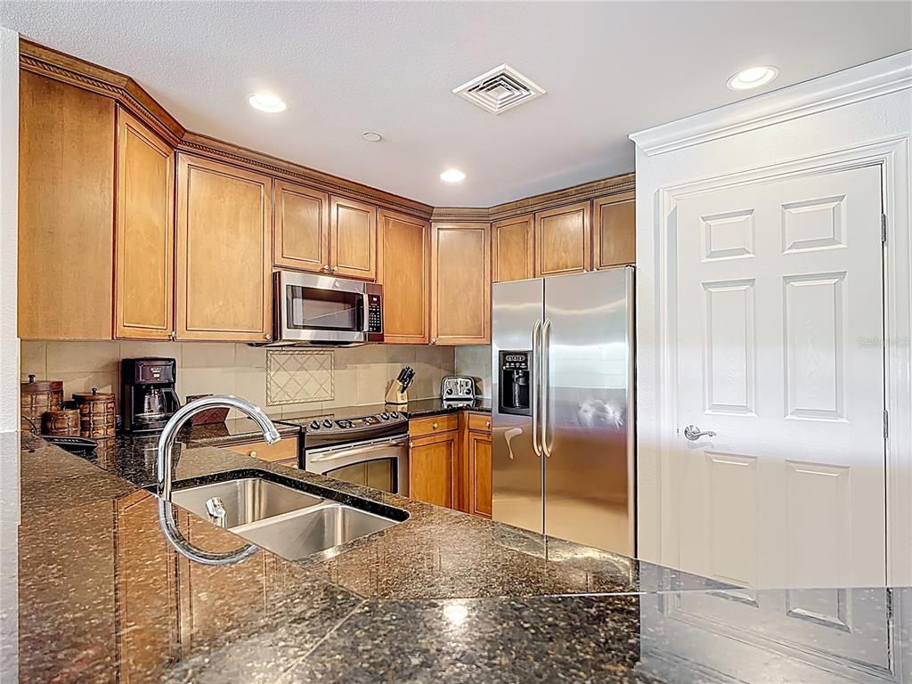 1356 Centre Ct Ridge Drive, Unit 103 Reunion, FL 34747 - Photo 12 of 53 a kitchen with stainless steel appliances granite countertop a refrigerator a stove and a sink with wooden floor