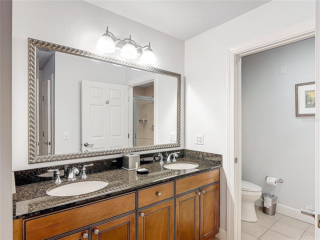 1356 Centre Ct Ridge Drive, Unit 103 Reunion, FL 34747 - Photo 29 of 53 a bathroom with a granite countertop sink a toilet and a mirror