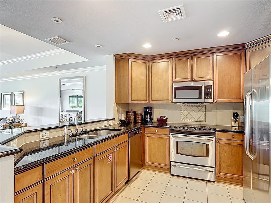 1356 Centre Ct Ridge Drive, Unit 103 Reunion, FL 34747 - Photo 7 of 53 a kitchen with granite countertop white cabinets sink and stainless steel appliances