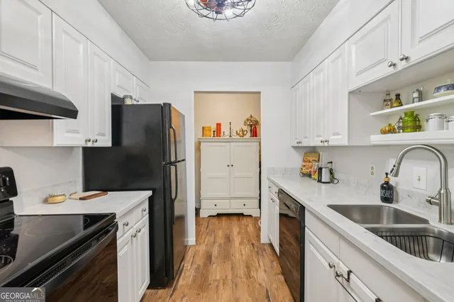 a kitchen with cabinets wooden floor and black appliances