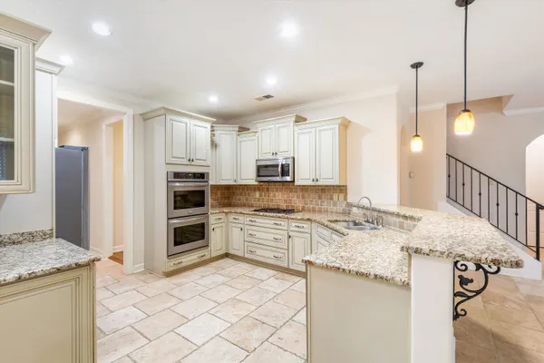 a kitchen with kitchen island granite countertop a stove a sink a refrigerator and white cabinets with wooden floor