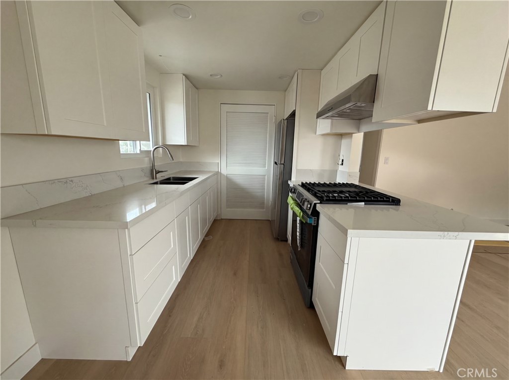 16752 Sims Lane, Unit A Huntington Beach, CA 92649 - Photo 2 of 8 a kitchen with granite countertop white cabinets and white appliances