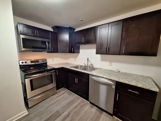 a kitchen with stainless steel appliances granite countertop wooden cabinets and a stove top oven