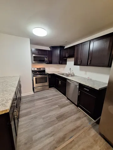 a kitchen with stainless steel appliances kitchen island granite countertop a stove a sink and a refrigerator