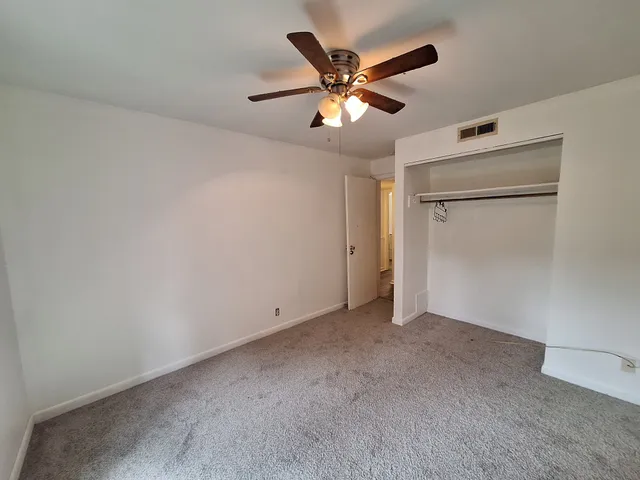 an empty room with closet and a ceiling fan