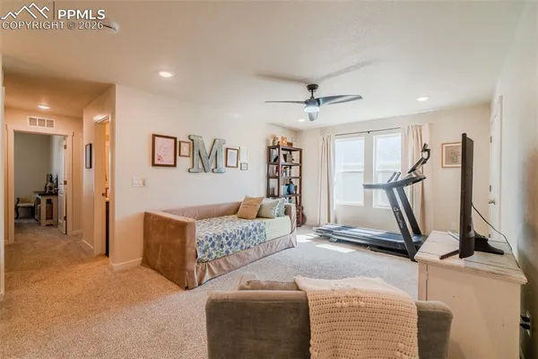 a living room with furniture gym equipment and a ceiling fan