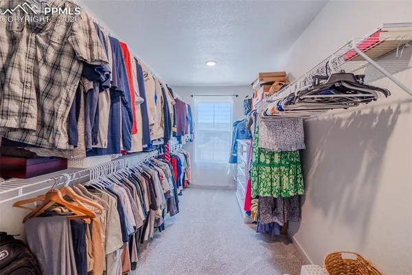 a view of walk in closet with clothes and shoes