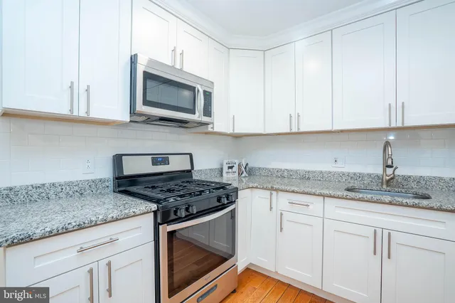 a kitchen with granite countertop white cabinets and stainless steel appliances