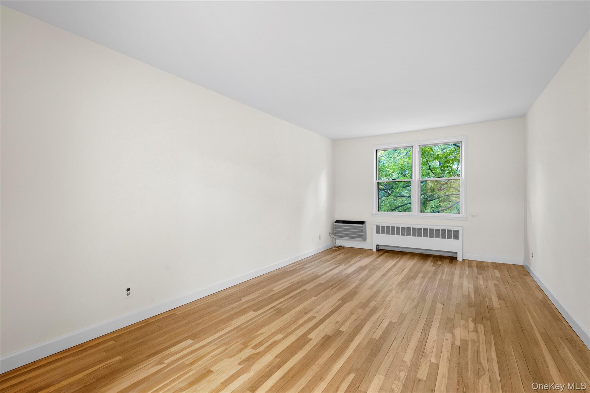 325 Palmer Terrace, Unit 2C Mamaroneck, NY 10543 - Photo 6 of 18 a view of an empty room with wooden floor and a window