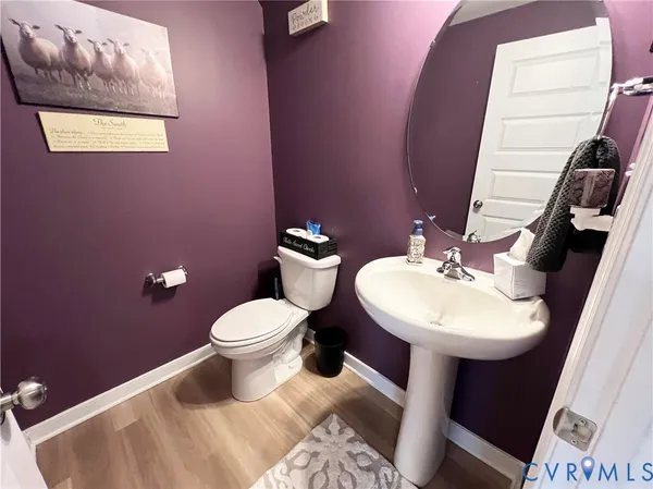 a bedroom with a bed and a lamp on dresser with wooden floor