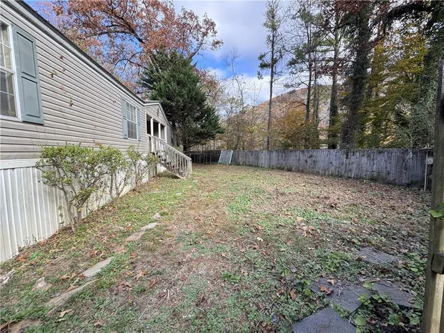 a view of a yard with large tree and wooden fence