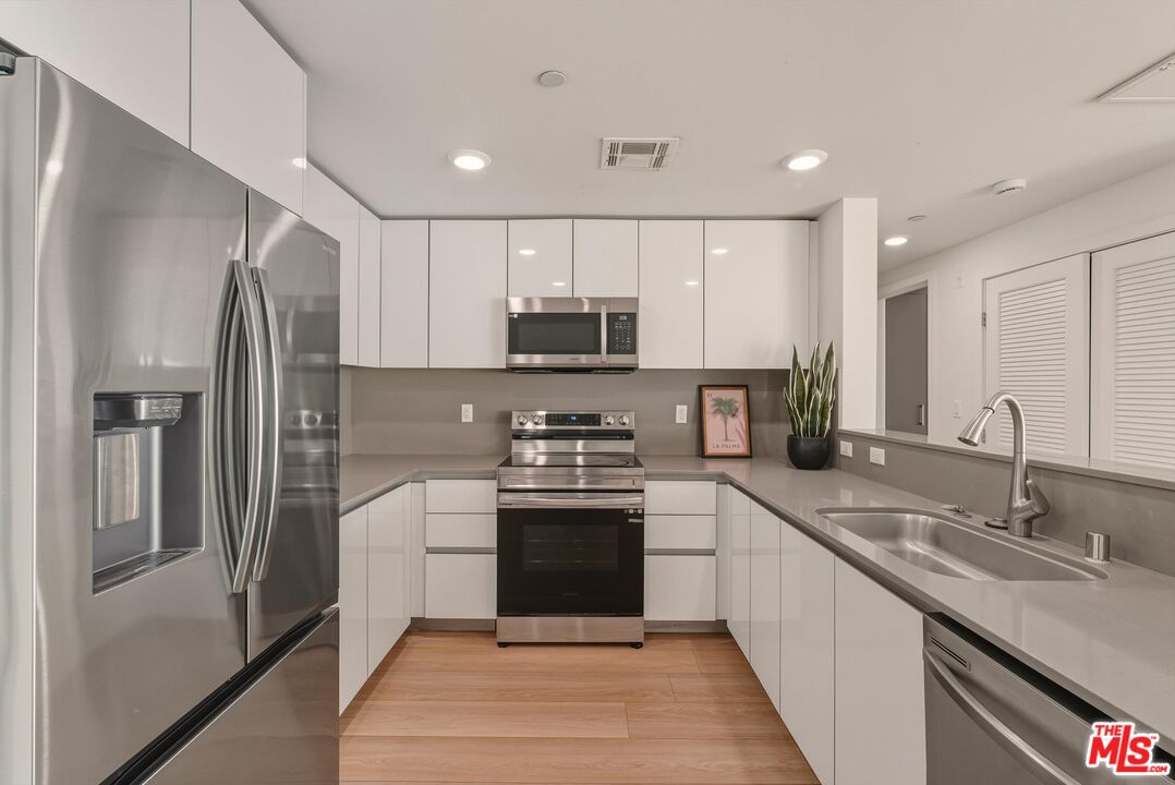1759 North Gower Street, Unit 404 Los Angeles, CA 90028 - Photo 5 of 23 a kitchen with stainless steel appliances granite countertop a sink and a refrigerator
