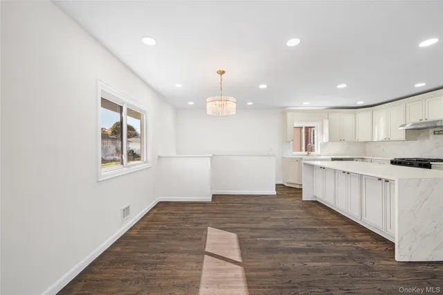 a large kitchen with kitchen island a island wooden floor and stainless steel appliances