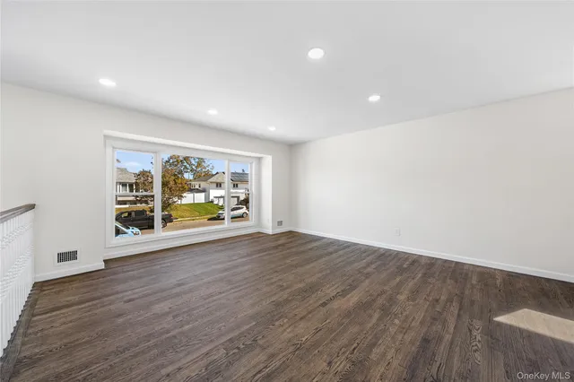 a view of an empty room with wooden floor and window