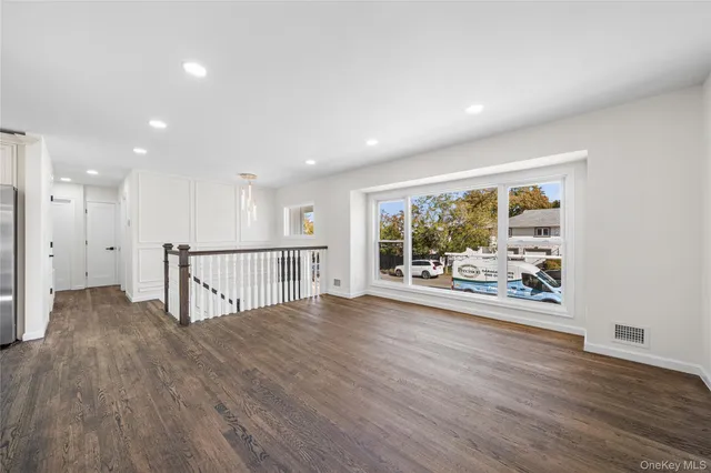 a view of an empty room with wooden floor and fan