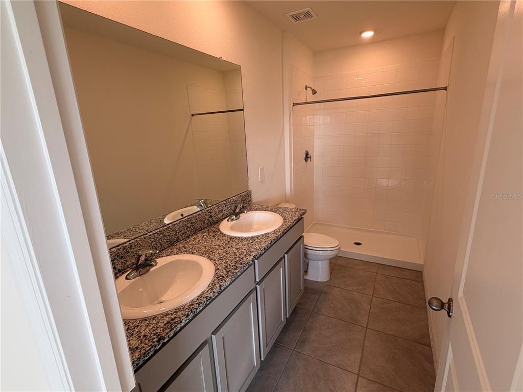 17534 Crescent Moon Loop Bradenton, FL 34211 - Photo 12 of 18 a bathroom with a granite countertop sink toilet and shower