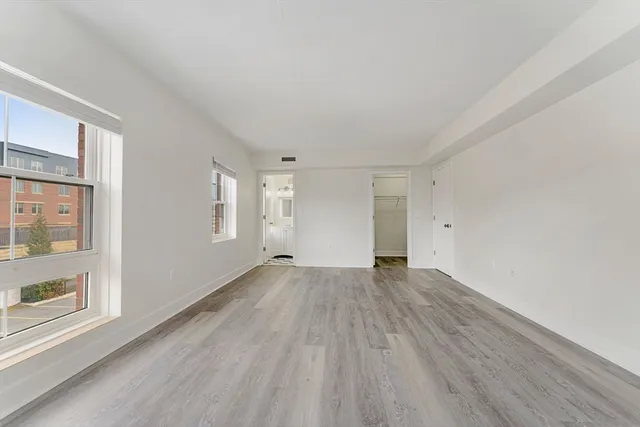 a view of an empty room with wooden floor and a window