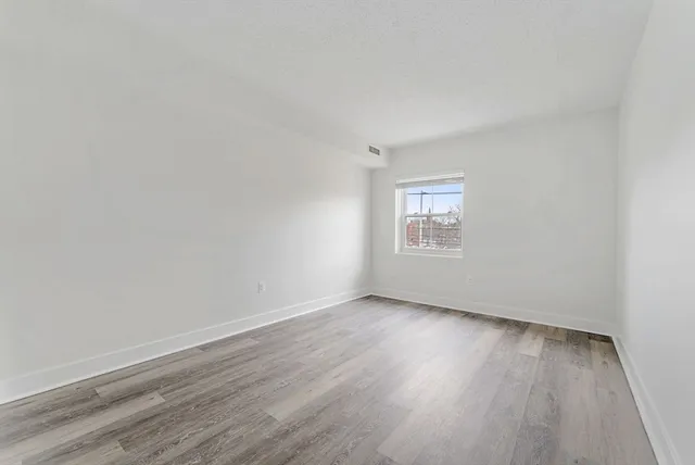 a view of an empty room with a window and wooden floor