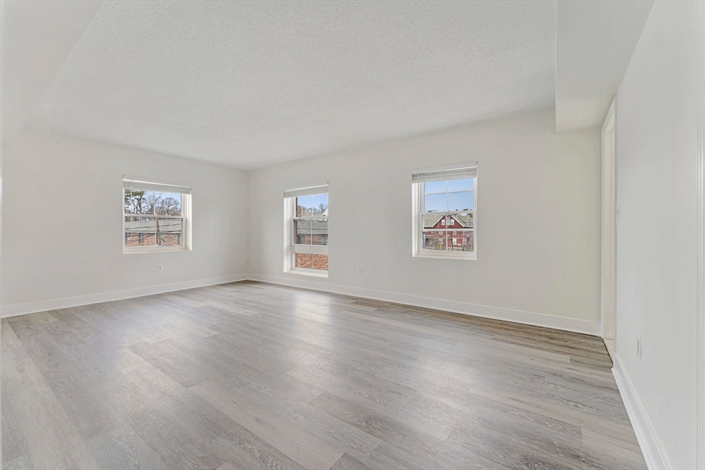 31 Spring Street, Unit 308 Watertown, MA 02472 - Photo 10 of 37 a view of an empty room with a window and wooden floor