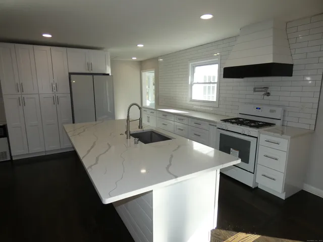 a kitchen with stainless steel appliances granite countertop a sink a stove and a refrigerator