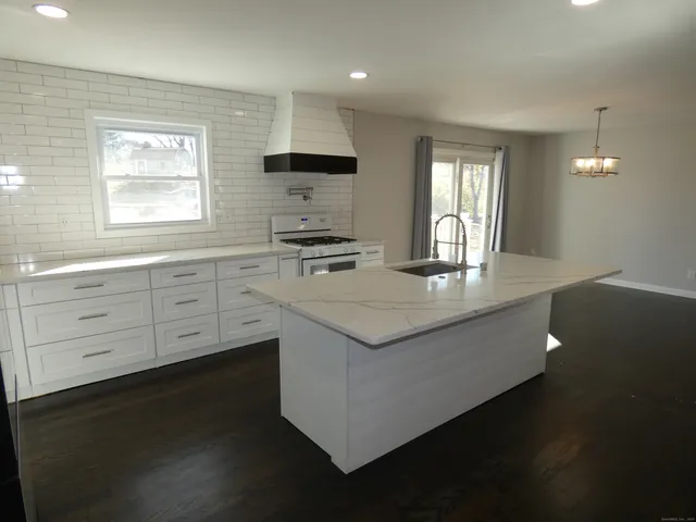a kitchen with kitchen island granite countertop a stove a sink and a refrigerator