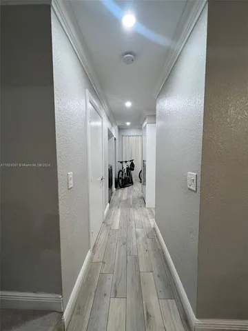 a view of a hallway with wooden floor and a bathroom