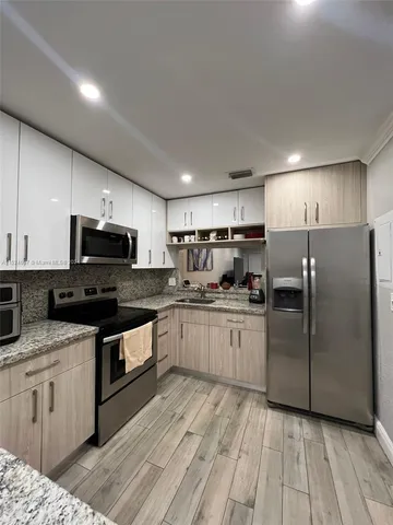 a kitchen with stainless steel appliances granite countertop a stove a sink and a refrigerator