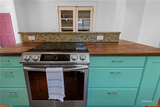 a kitchen with kitchen island granite countertop a stove and a wooden floors
