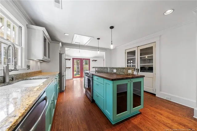 a kitchen with kitchen island wooden floor center island and stainless steel appliances
